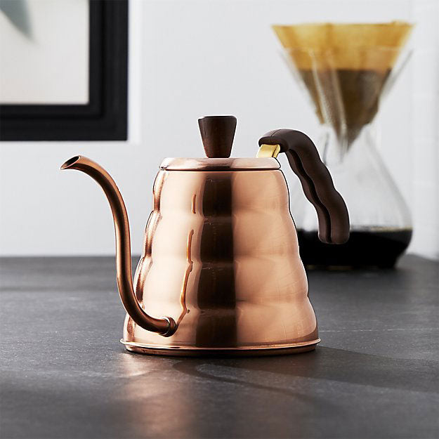 Copper coffee kettle on a dark surface with a blurred background