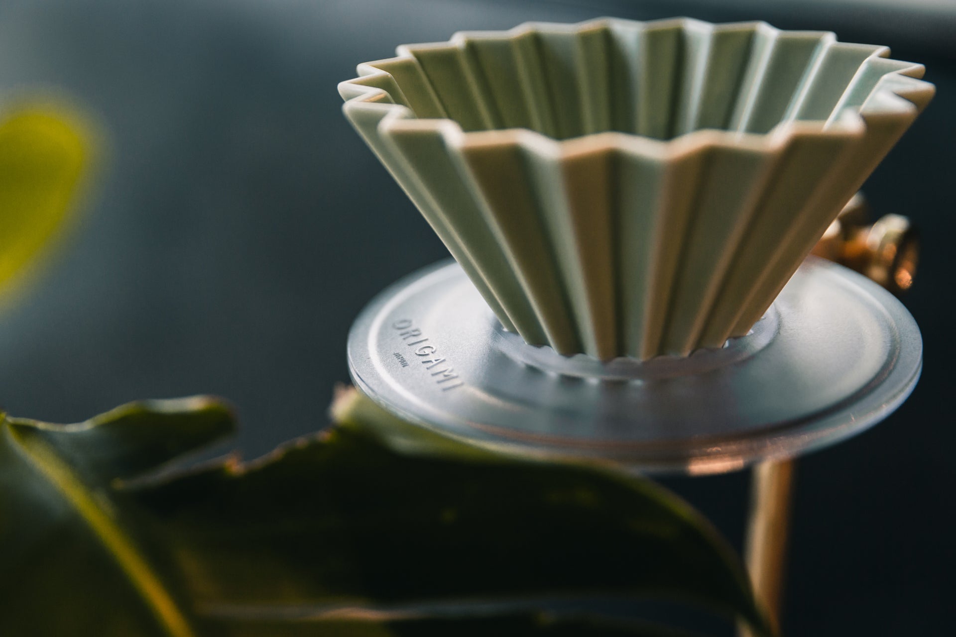 Origami Dripper with Origami Resin Dripper Holder with blurred green leaves in the foreground
