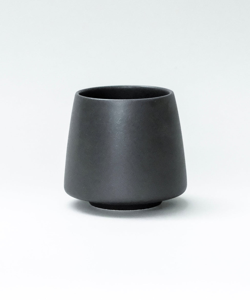 Black origami ceramic flavor cup on a white background