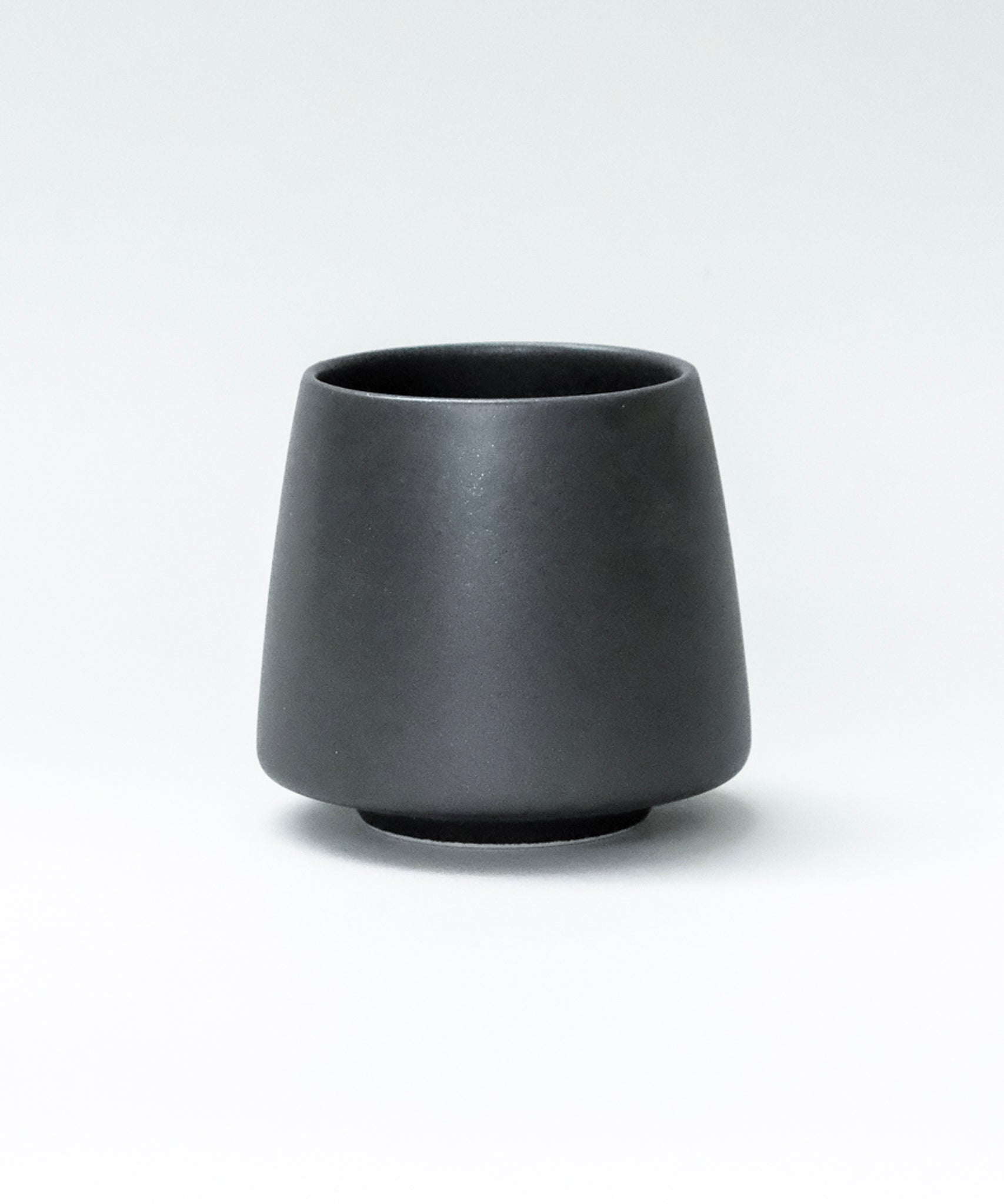 Black origami ceramic flavor cup on a white background