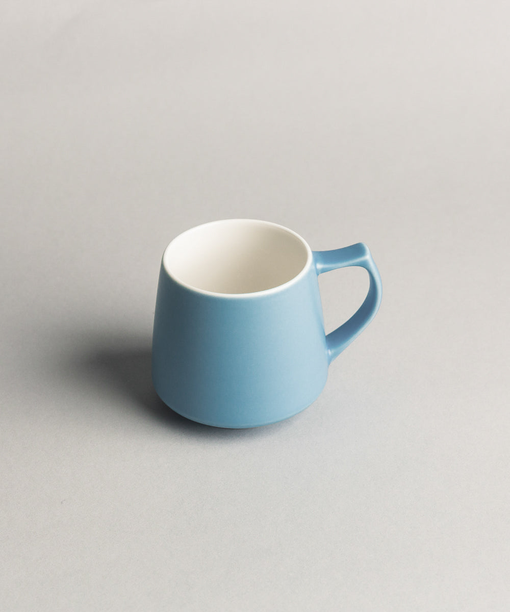 Blue origami aroma ceramice mug with white interior on a gray background