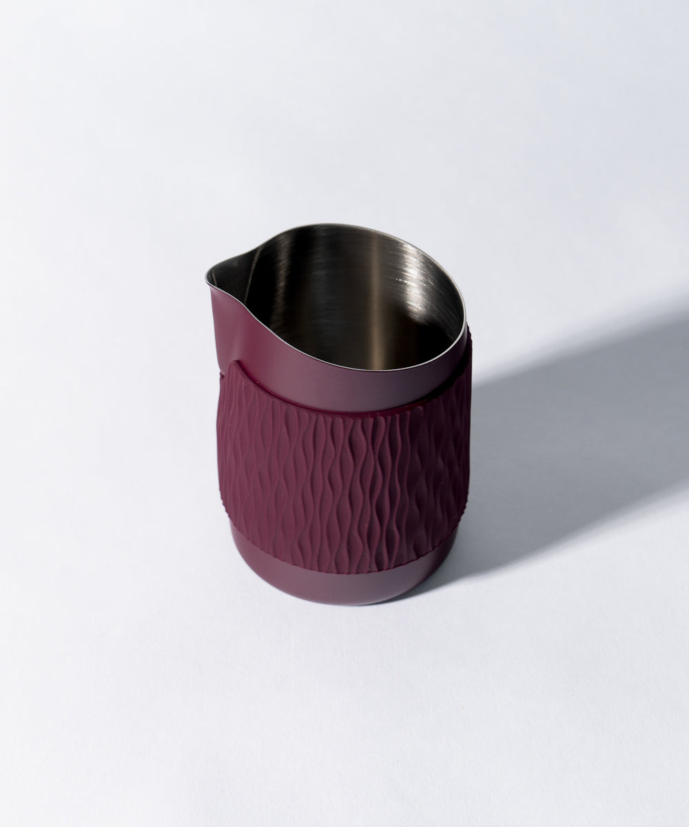 WPM Pitcher in Aubergine shown from the side, featuring a sleek handleless design for latte art