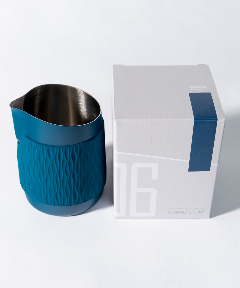 WPM Pitcher in Marina Blue shown from the side, featuring a sleek handleless design for latte art pictured with the packaging box