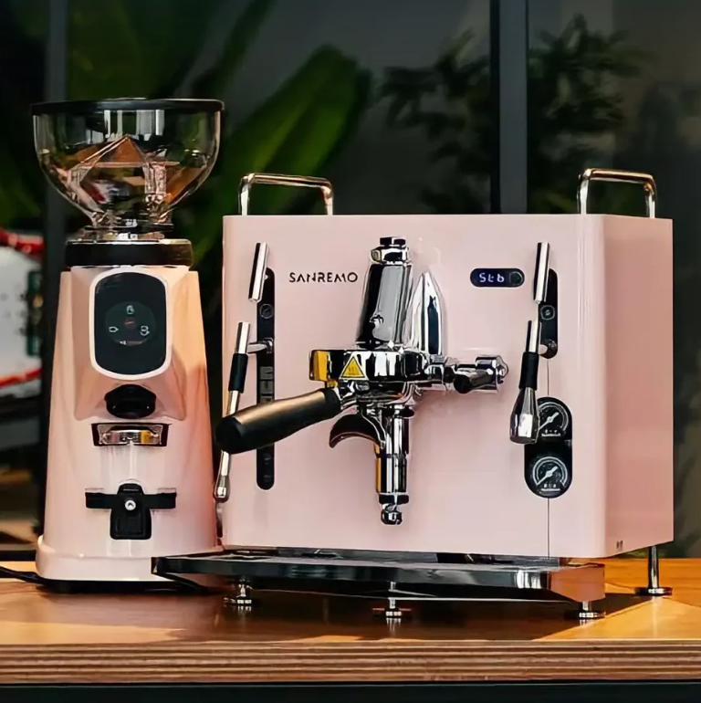 Sanremo CUBE A R pink  home espresso machine cube and grinder on a wooden surface with blurred greenery in the background