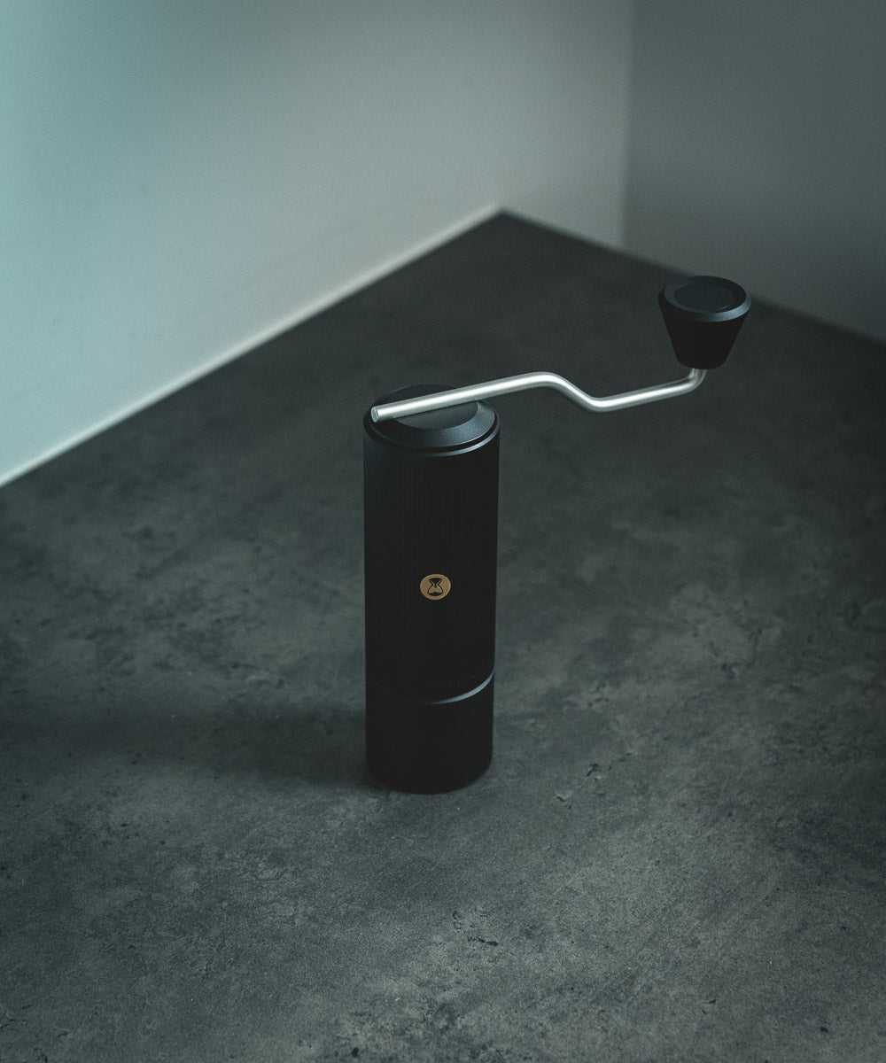 Black Timemore Manual Hand Coffee Grinder in the model Chestunt X Lite - on a deep grey surface with gray background