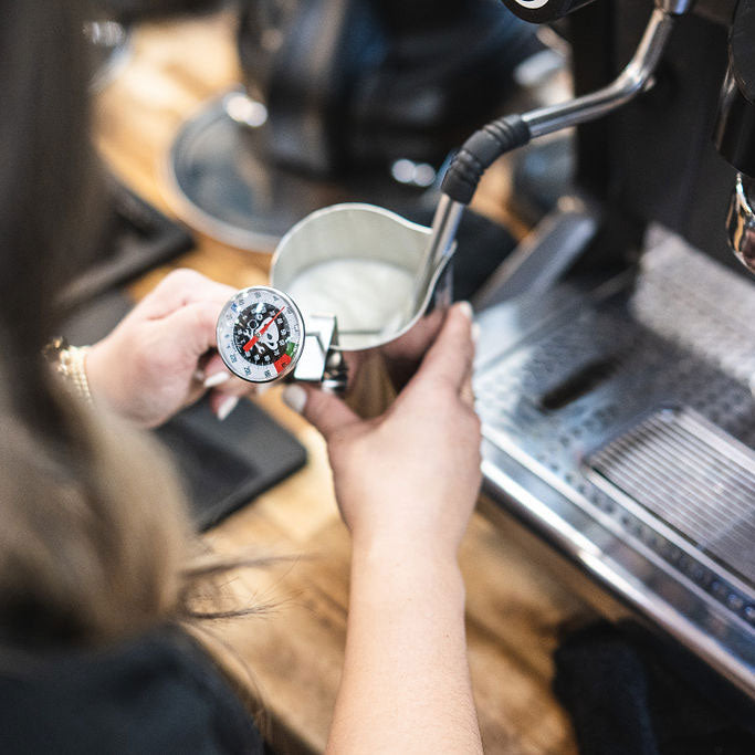 Person using a coffee grinder with a focus on the action of grinding coffee beans.